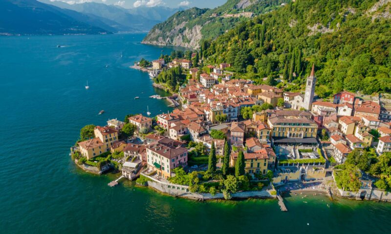 Menaggio, Como Lake. Aerial panoramic view of town surrounded by mountains, blue sky and turquoise water and located in Como Lake, Lombardy, Italy Varenna town, Como Lake. Aerial panoramic of town surrounded by mountains architecture, como, destination, europe, european, italian, italy, lago di como, lake, landscape, lombardy, menaggio, mountain, port, tourism, tourist, building, church, entrance, harbor, italia, lakeside, landmark, lombardia, old, sky, tower, town, travel, turquoise, walkway, waterfront, window, village, scenery, attraction, como lake, coast, lago como, panorama, touristic, aerial, drone, varenna, alps, scenic, mountains, coastline, aerial view, lake como