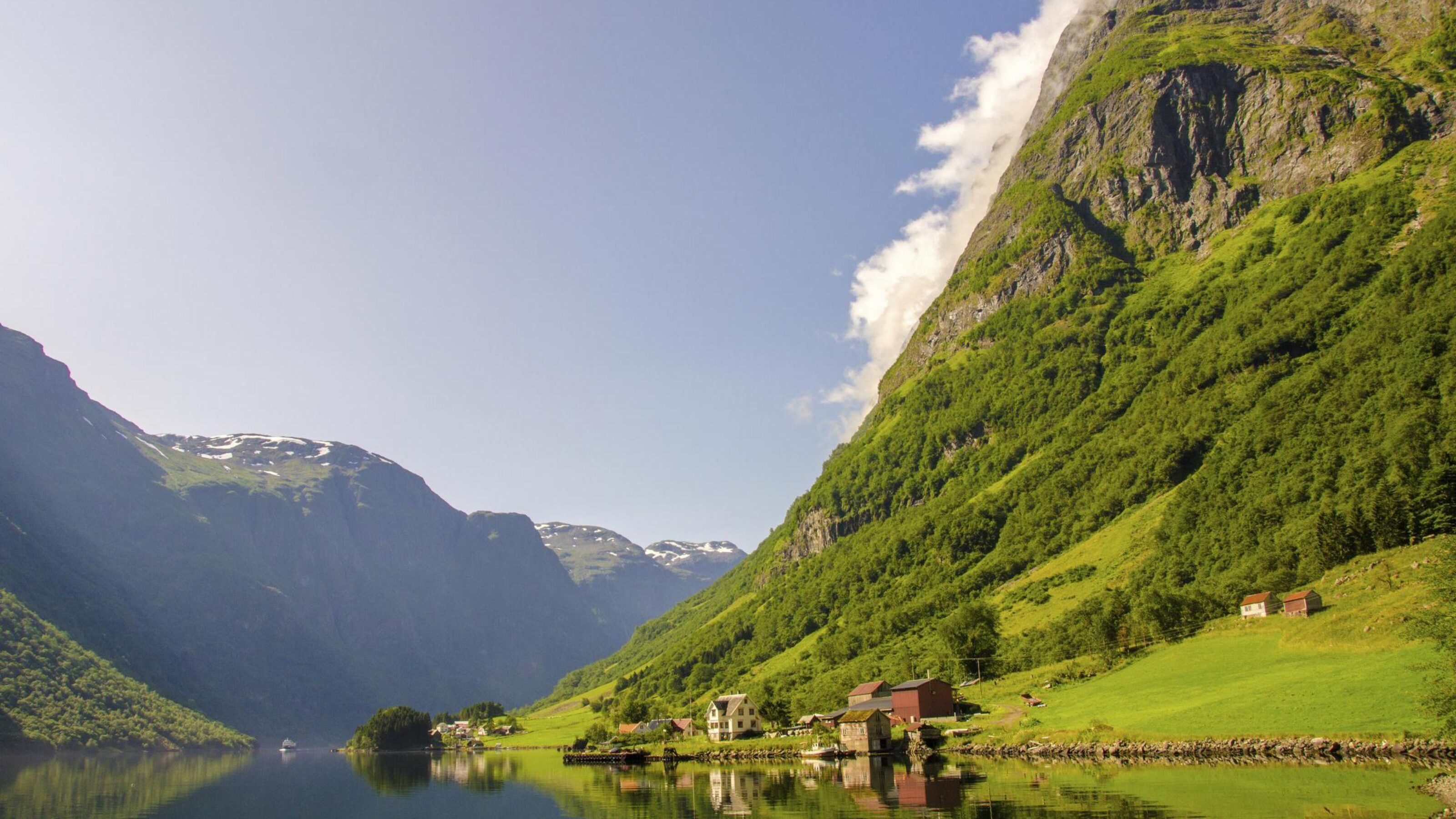 Verdant valley dramatically dropping into the reflective water, Bergen, Norway