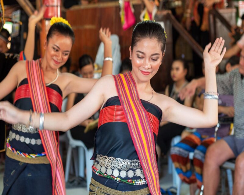 Dancers in traditional black and red woven clothing performing during luxury Borneo vacations.