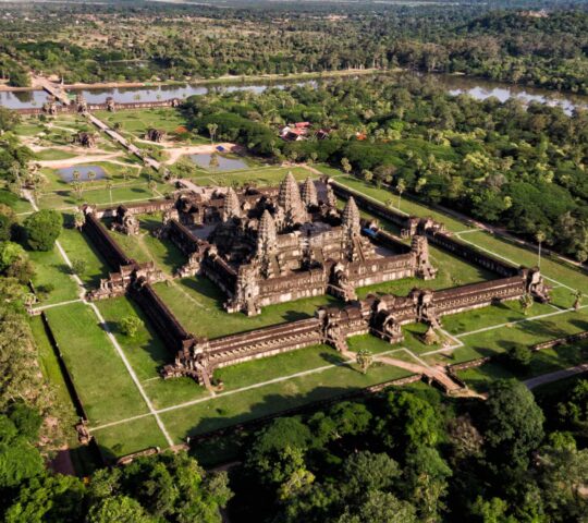A sweeping aerial view of Angkor Wat, showcasing the temple complex surrounded by lush green jungle