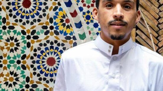 Portrait of a young Berber man holding a vegetarian couscous plate. Marrakesh, Morocco.