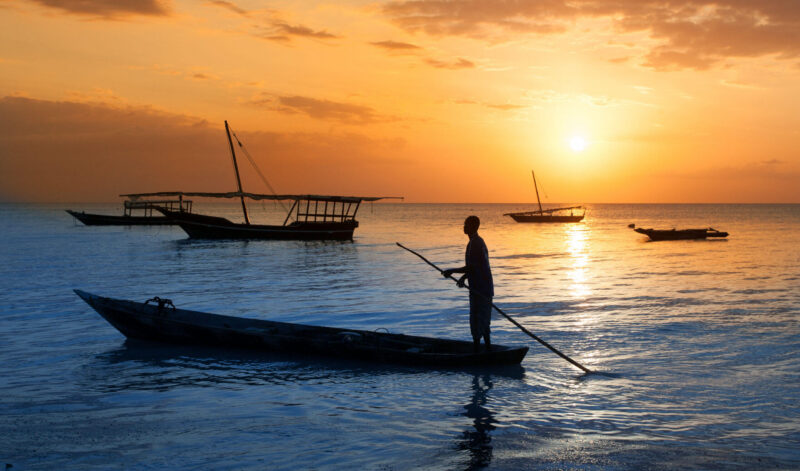 Man on a traditional boat off the coast of Zanzibar at sunset