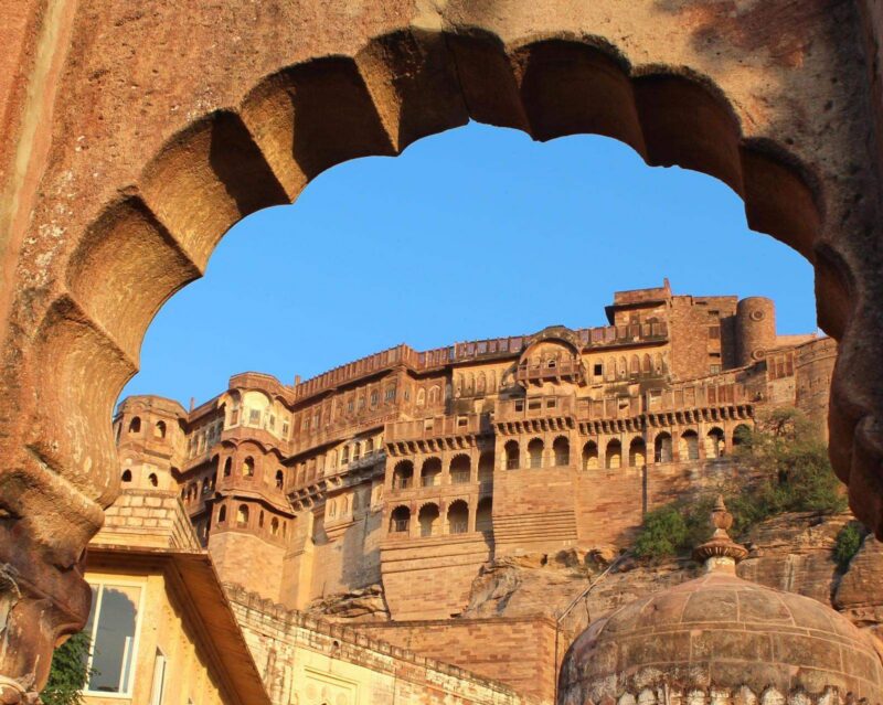 A carved archway frames the sandstone ramparts of Mehrangarh Fort in Jodhpur, India.