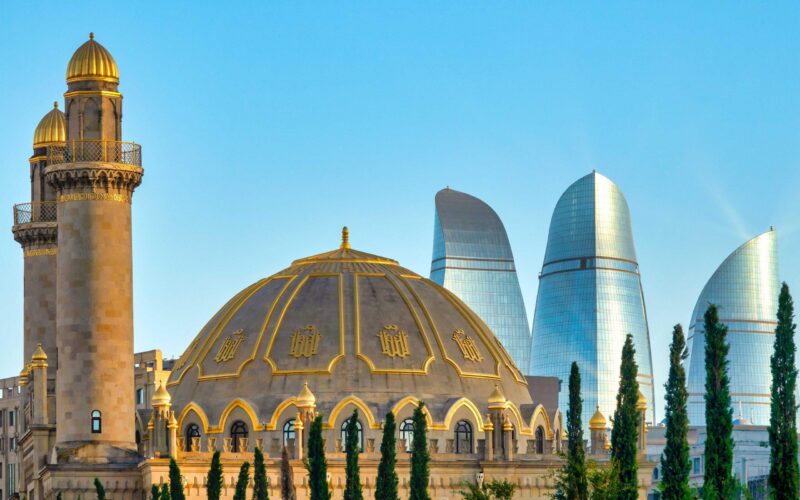 The stone dome of Bibi-Heybat Mosque sits before Baku's glass Flame Towers in Azerbaijan.