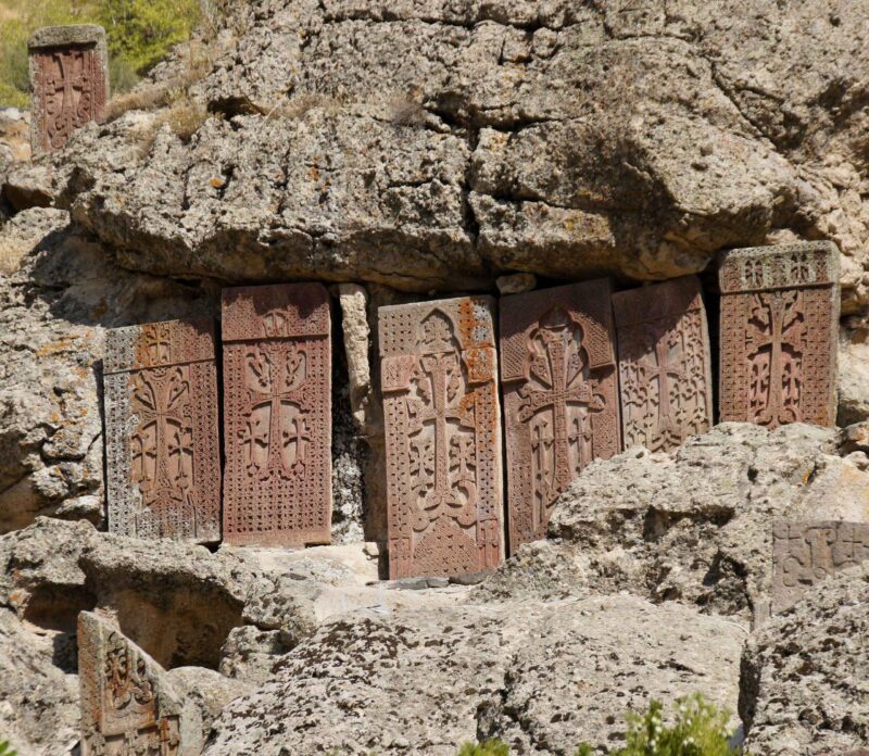 Intricately carved stone khatchkars stand on a rocky hillside at Geghard Monastery (Monastery of the Spear), Garni, Armenia.