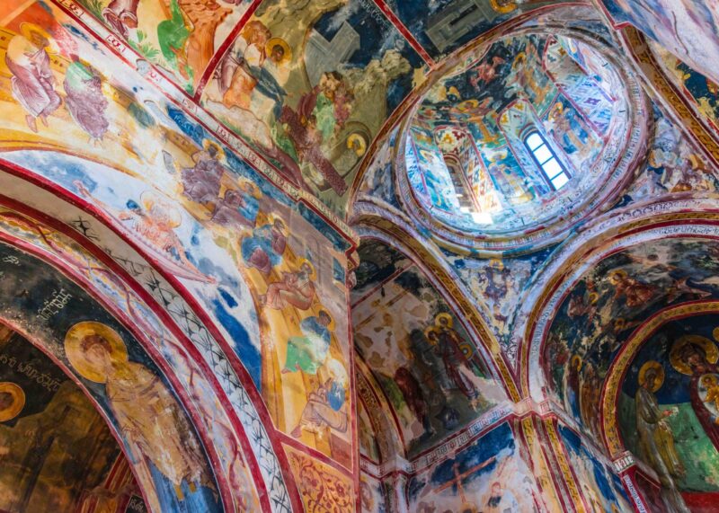 Vivid medieval frescoes cover the vaulted arches and dome inside Gelati Monastery, Georgia.