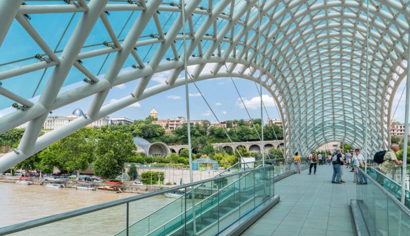 Pedestrians cross the glass canopy of the Bridge of Peace over the Kura River in Tbilisi, Georgia.