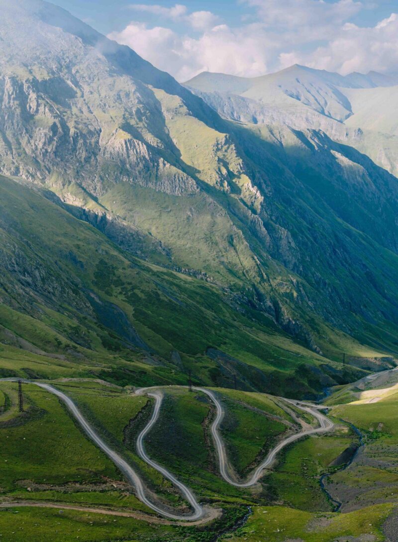 Winding hairpin turns of the Abano Pass cut through steep green slopes in Tusheti, Georgia.