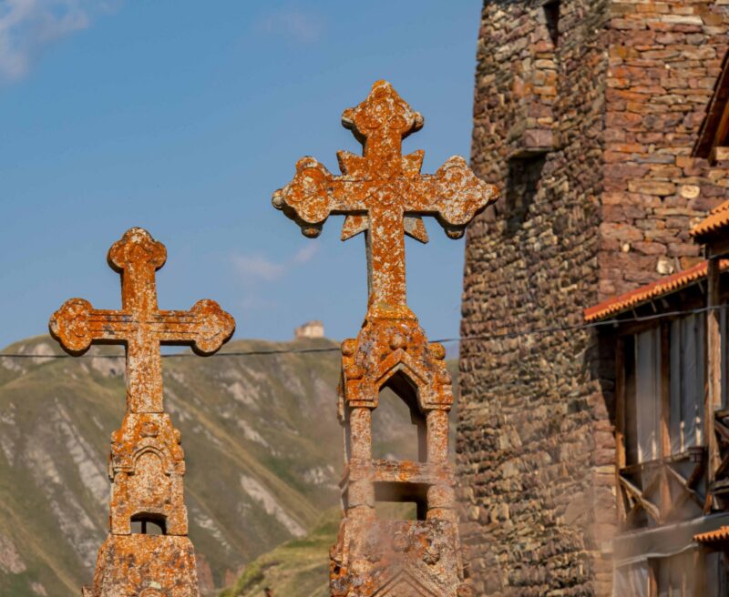 Orthodox crosses in Truso valley in Kazbegi district in the Greater Caucasus Mountains, Mtskheta-Mtianeti region, Georgia. Headstone marking a grave in the foreground. Russian border.Zakagori Fortress