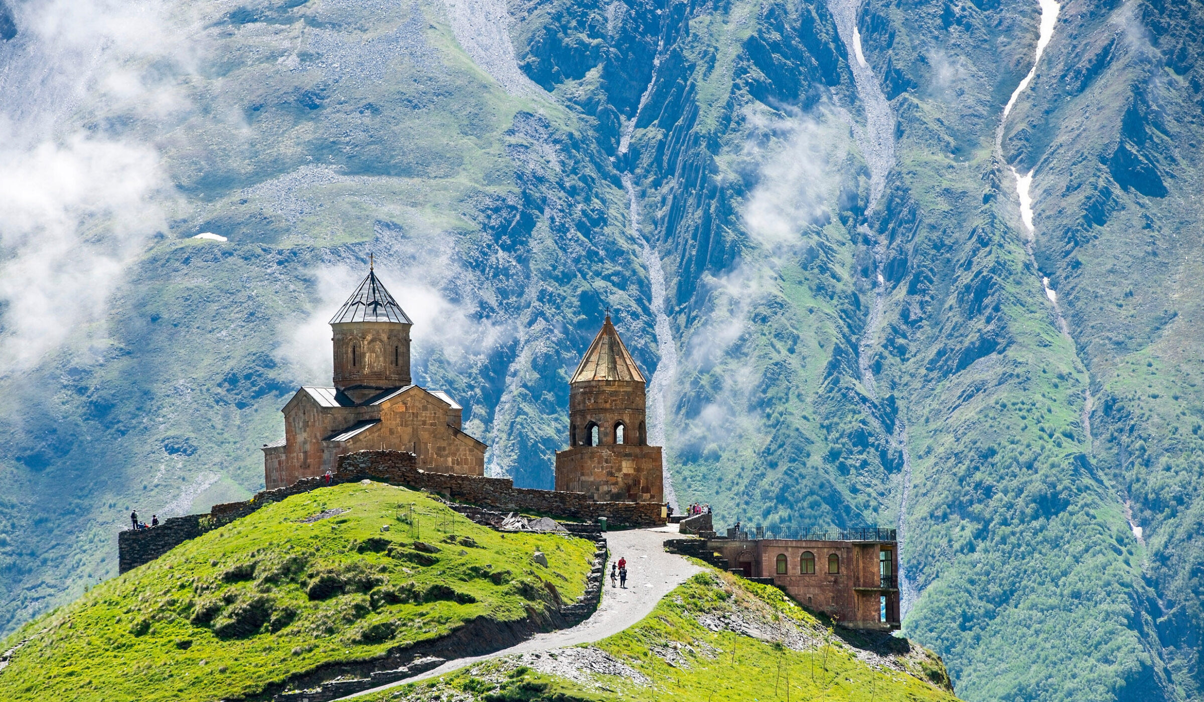 Gergeti Trinity Church on a green mountain ridge in Georgia during luxury Central Asia tours.