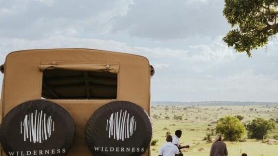 A small group of travellers and their safari guides stopping for lunch next to their safari vehicle, Serengeti National Park, Tanzania.