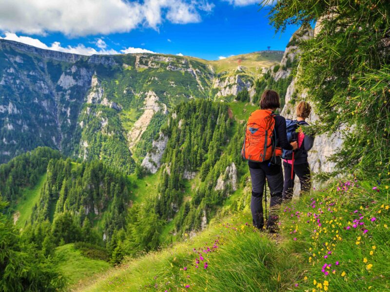 Woman’s hiking team with colorful backpacks walking on narrow trail,Bucegi mountains,Carpathians,Transylvania,Romania,Europe