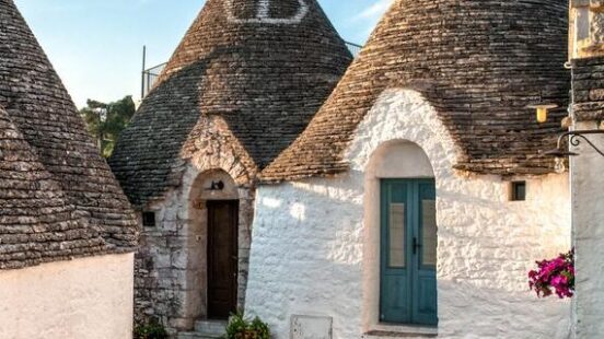 Conical roofs of traditional trulli houses in a sunny village during luxury Puglia vacations.