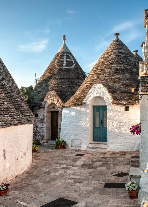 Conical roofs of traditional trulli houses in a sunny village during luxury Puglia vacations.