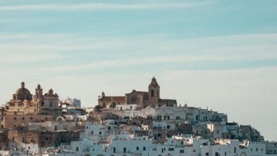 View of a sprawling white hilltop town with historic cathedrals for luxury Puglia holidays.
