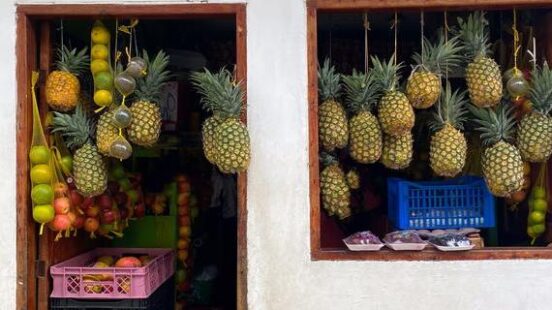 Fruit Shop Displaying Hanging Pineapples and Assorted Produce in Colombia