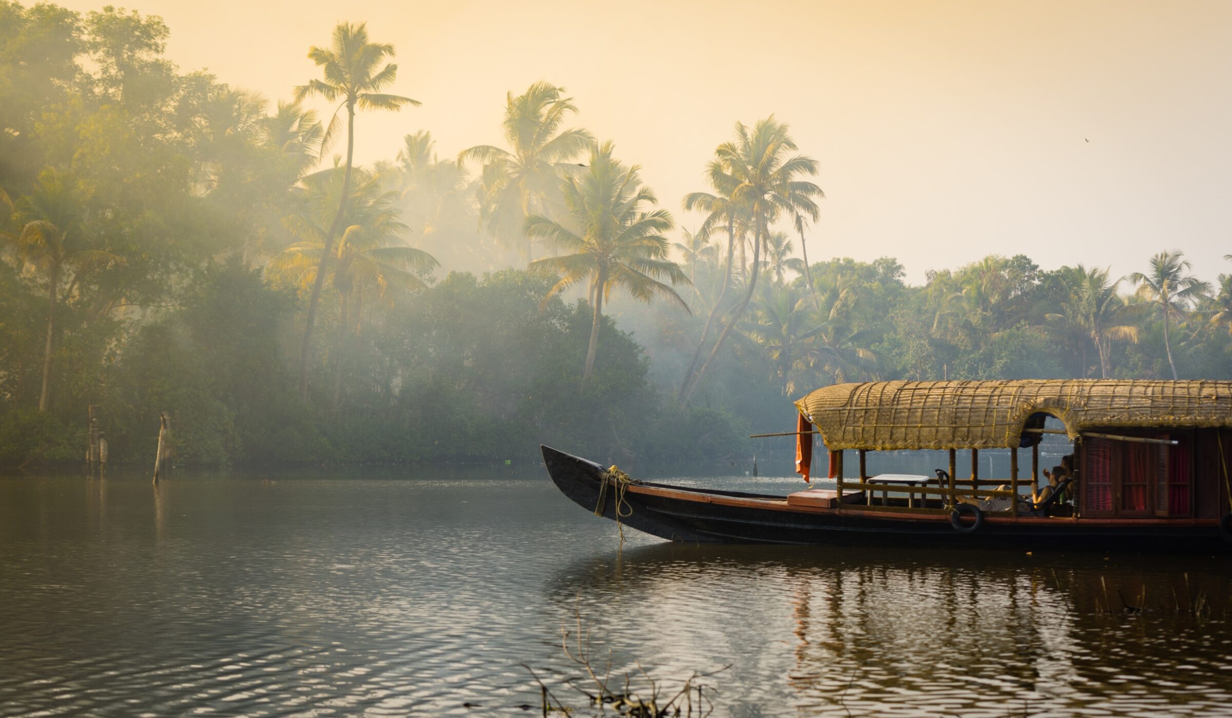 A traditional house boat is anchored on the shores of a fishing lake in Kerala's Backwaters, India.