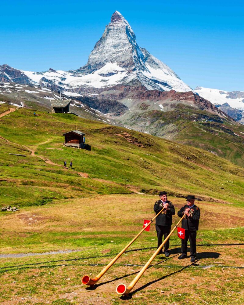 ZERMATT, SWITZERLAND – JULY 16, 2019: Swiss alphorn blowers are playing music near the Matterhorn mountain in the Alps, located between Switzerland and Italy