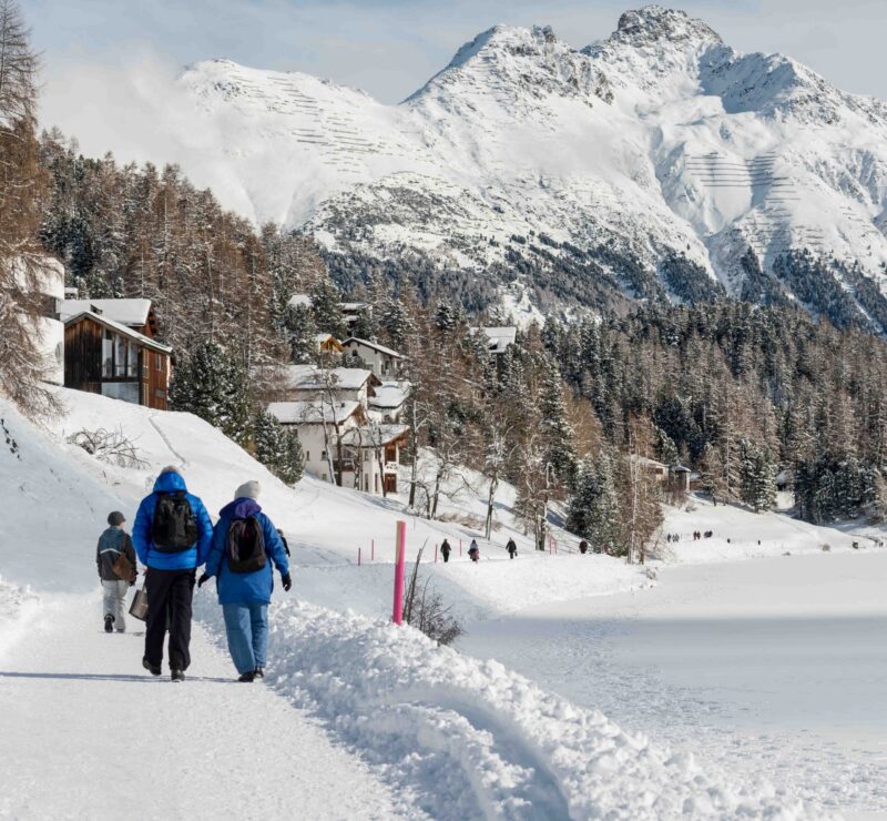 People walking along side the St Moritzersee in the Emgadin valley, Switzerland in winter.