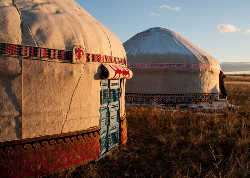 Two felt yurts with ornate patterns in a dry field, a common sight on luxury Mongolia trips.