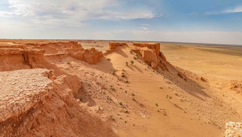 Wide view of red sandstone cliffs and desert plains, a landscape highlight of luxury Mongolia tours.