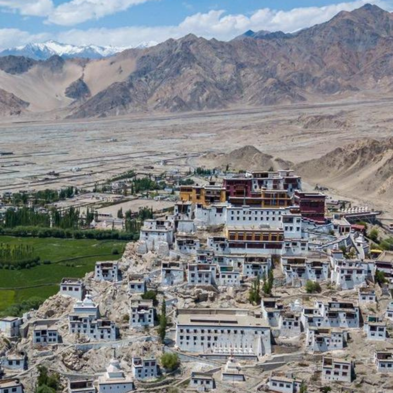 Thiksey Monastery rises in white and red tiers above the Indus Valley, framed by barren Himalayan peaks.