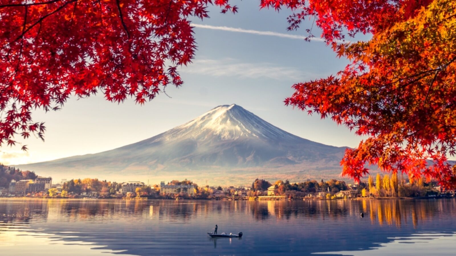 Mount Fuji viewed through red autumn leaves over a calm lake during luxury Asia grand tour vacations.