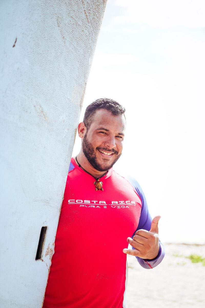 surfer with thumb up holing surf board
