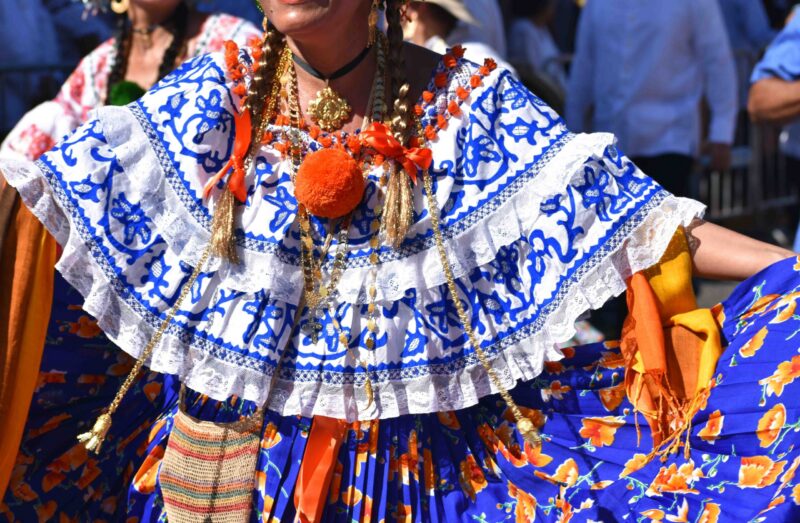 Close-up of intricate hand embroidery and gold jewellery on a traditional Panamanian pollera dress.