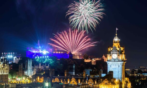 Colorful fireworks display over Edinburgh Castle and the cityx27;s historic landmarks at night.