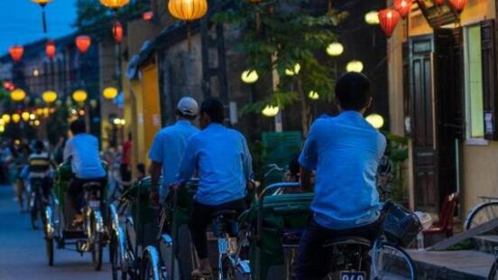 Cyclists on a street light by lanterns in Hoi An, Vietnam
