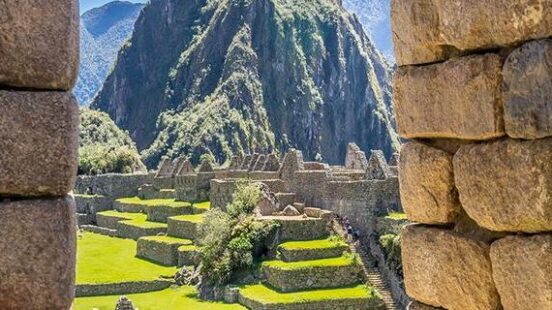 A view of Machu Picchux27;s stone structures and Huayna Picchu mountain framed through a stone window.