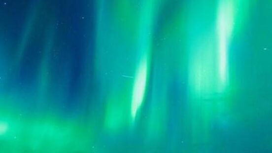 Two silhouettes stand under vibrant green aurora borealis bands in the Arctic night sky. - Northern Lights