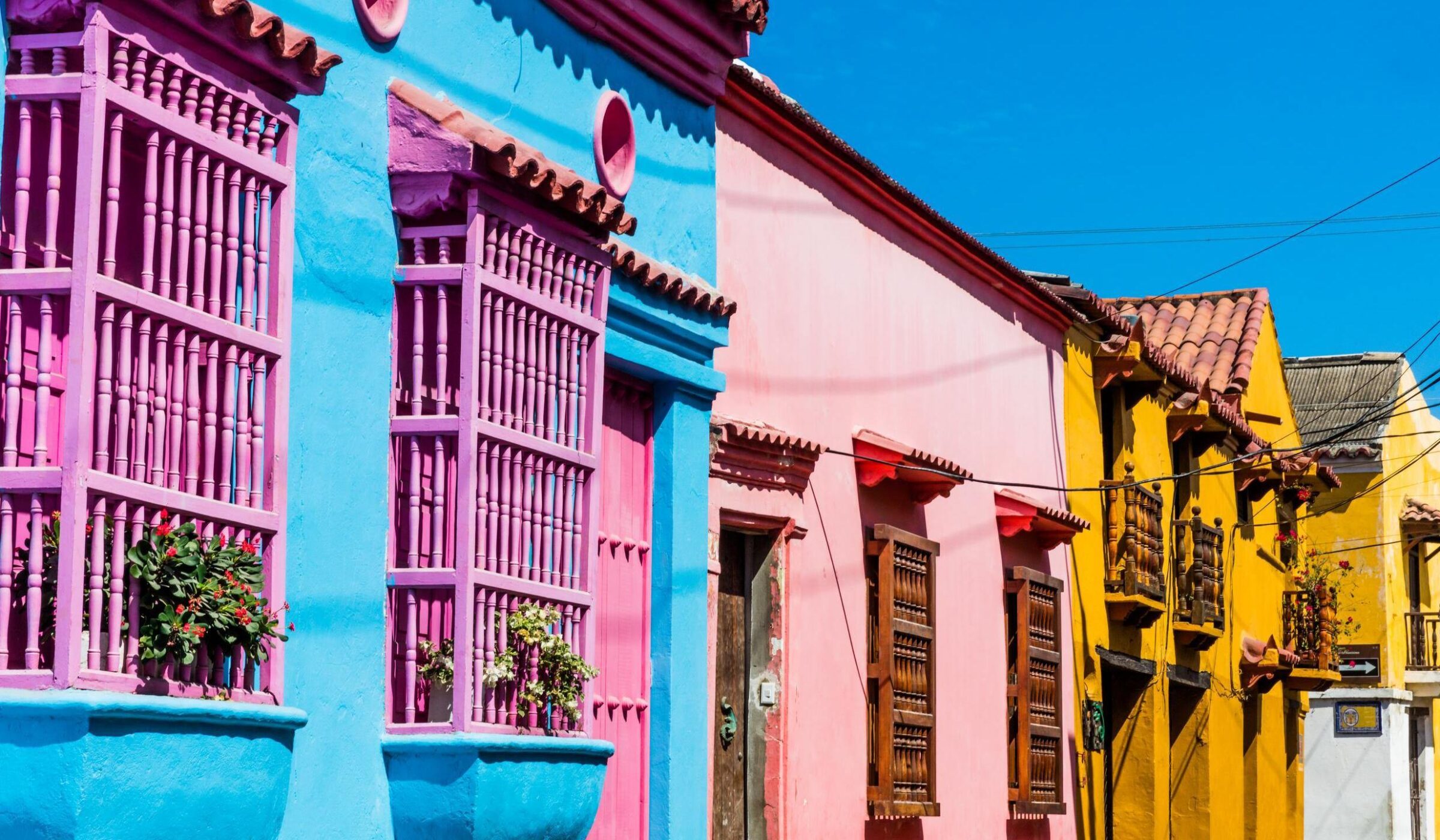 Rainbow coloured buildings with bright window shutters in a street in Cartagena Colombia