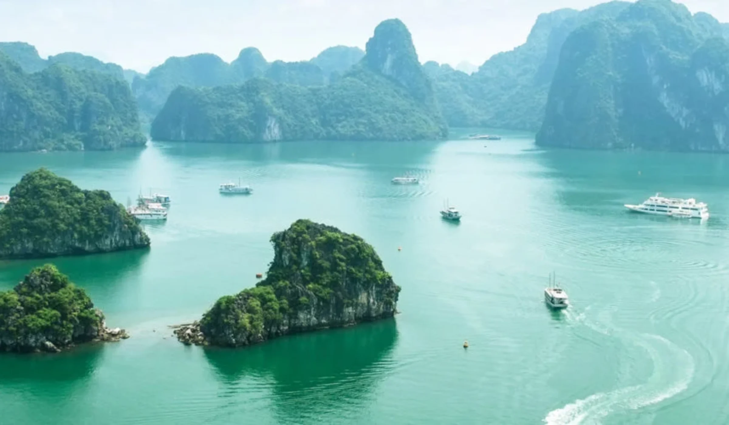 High-angle view of green limestone karsts and islands scattered across the turquoise waters of Ha Long Bay, Vietnam.