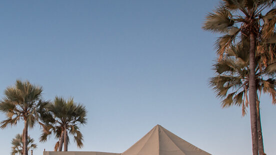Jackx27;s Camp exterior with palm trees at dusk, Botswana.