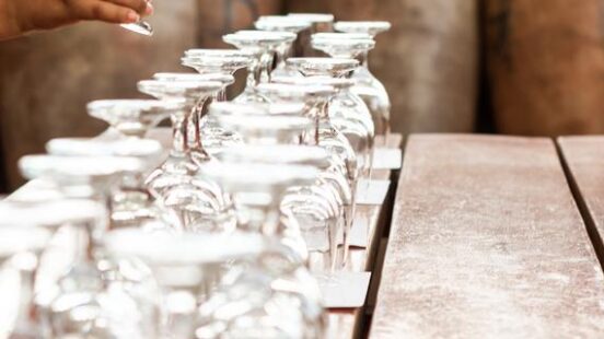 pour pisco in a glass with pisco cantaros as background