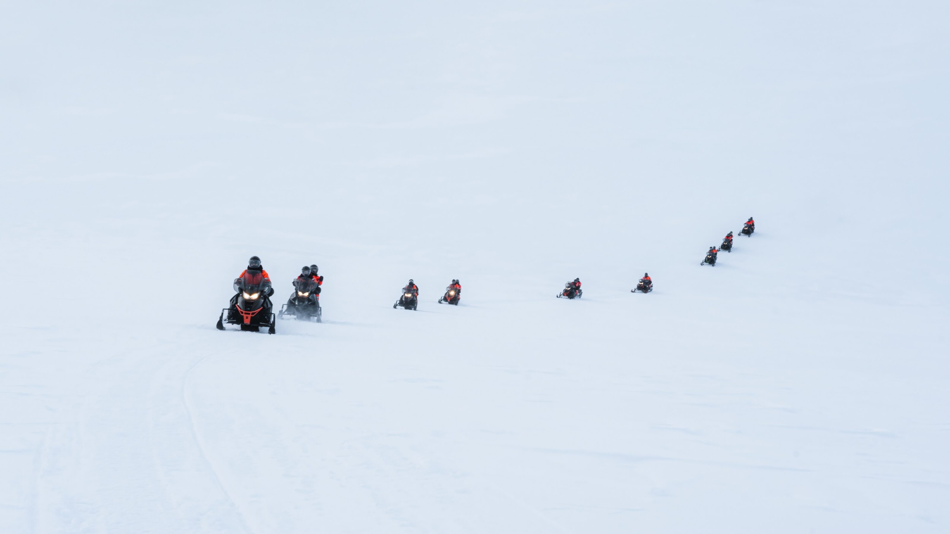 Group of tourists riding snowmobiles on snowy glacier mountain summit at Iceland