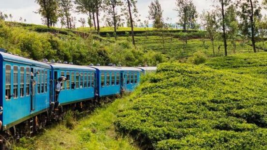 A blue train curves through green hillside in Sri Lanka
