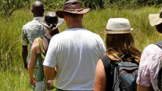 A group of tourists walk single file following a local guide