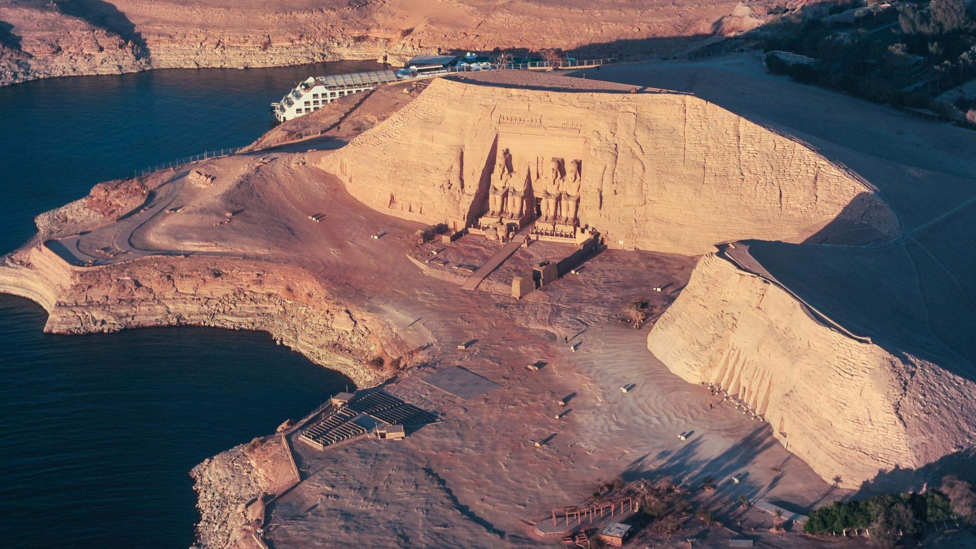 Aerial view of the Abu Simbel temples beside a lake at sunset.