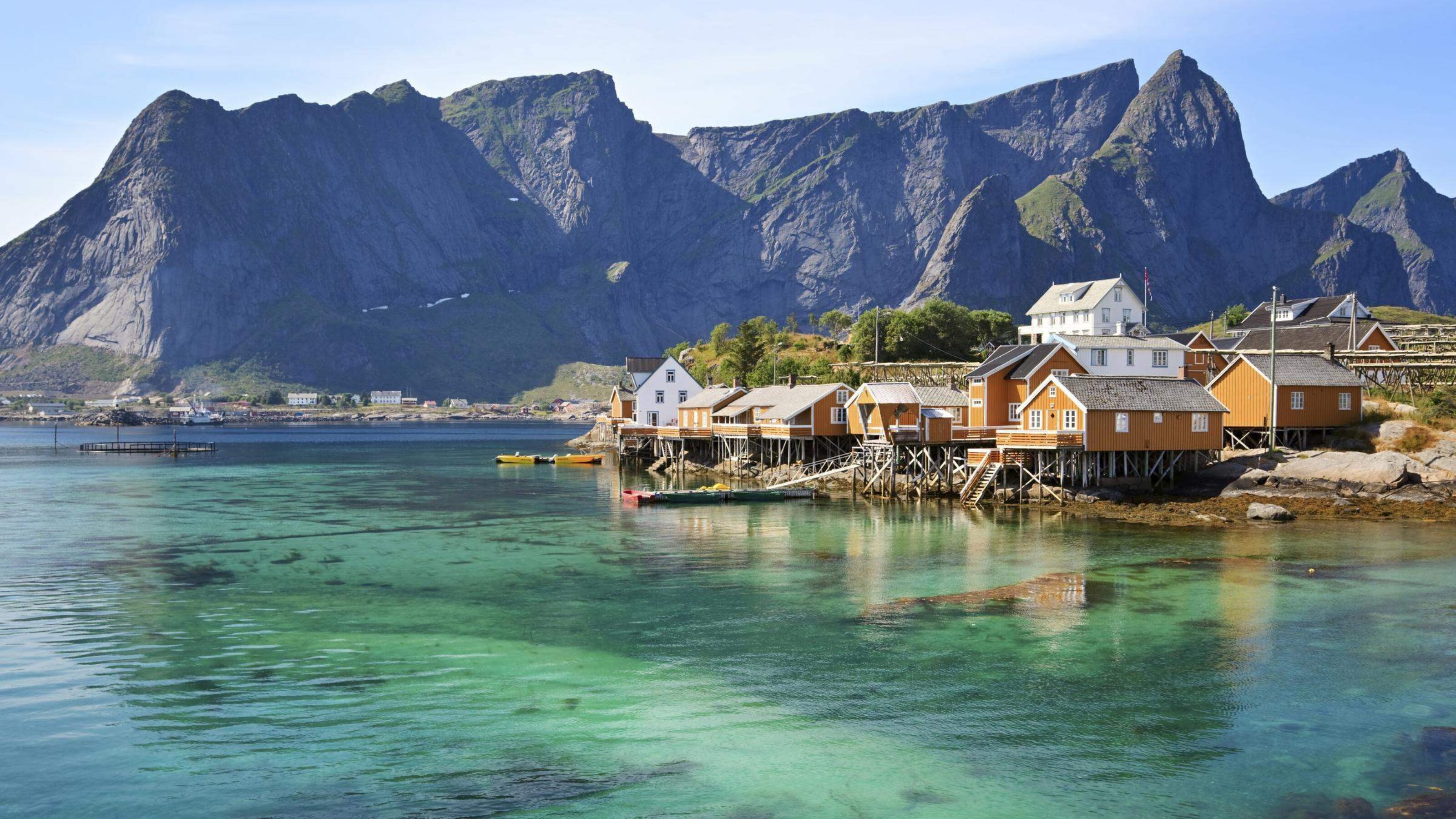 Scenic view of wooden houses along the coastline with mountains in the background.