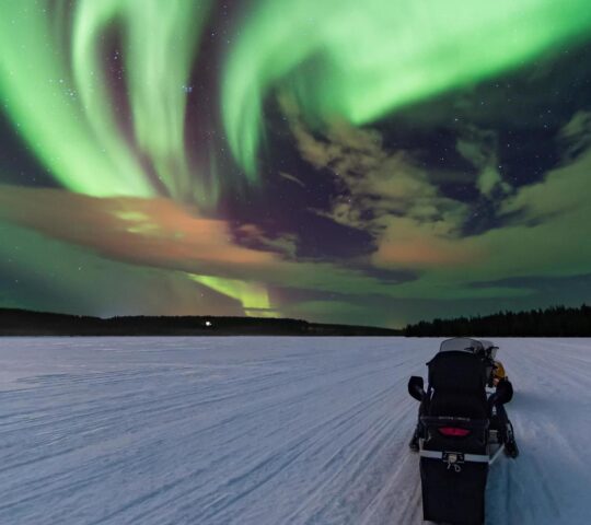 Snowmobiling beneath the northern lights