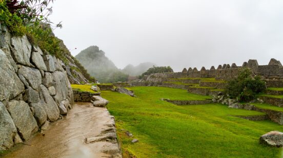 Misty view of Machu Picchux27;s ancient stone ruins and terraces with lush greenery.
