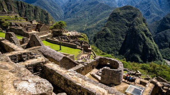Ancient stone ruins of Machu Picchu with green terraces and mountain backdrop.