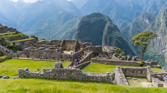 Visitors exploring the ancient Inca ruins of Machu Picchu set against a backdrop of lush mountains.