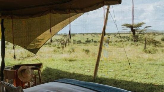 A luxury tent with a bed facing the open savannah.