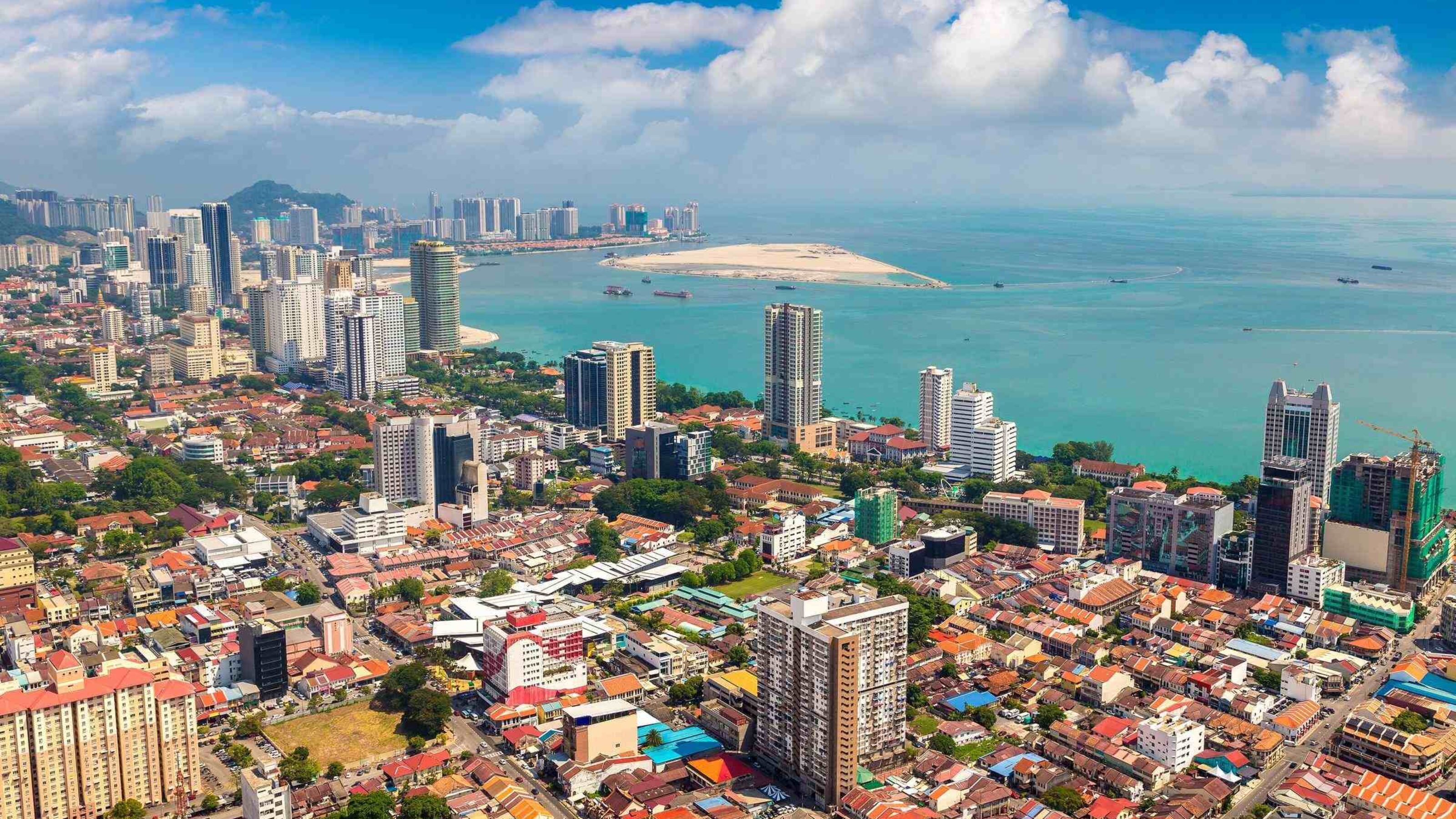 Aerial view of a coastal city with dense buildings and blue sea.
