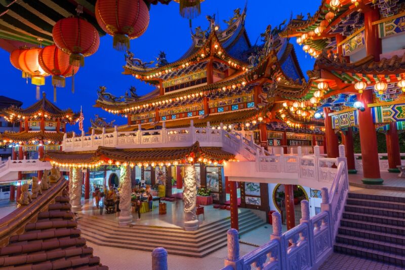 Illuminated traditional Chinese temple with intricate designs and red lanterns at dusk.