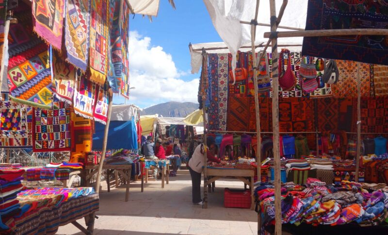 Colorful textile market stalls with hanging fabrics under a blue sky.